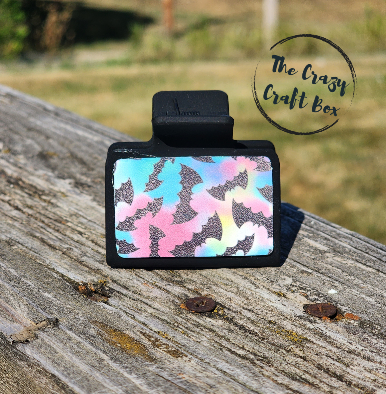 Whiskers n Bows black hair claw clip featuring a colourful iridescent bat pattern, resting on a wooden surface.
