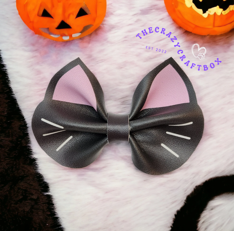 Whiskers n Bows black faux leather cat ear hair bow with pink accents and white whisker details on a fuzzy background