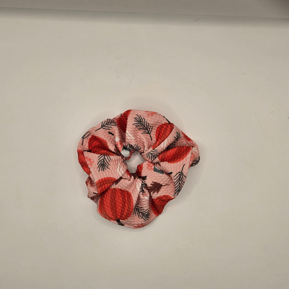 Whiskers n Bows pink fabric scrunchie featuring a festive red pumpkin and pine leaf print for autumn hair styling.