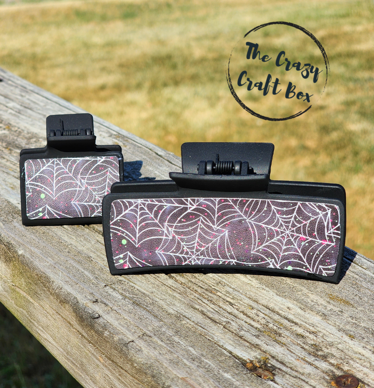 Whiskers n Bows Halloween claw clips in 4-inch and 2-inch sizes featuring a black spiderweb pattern with glitter.