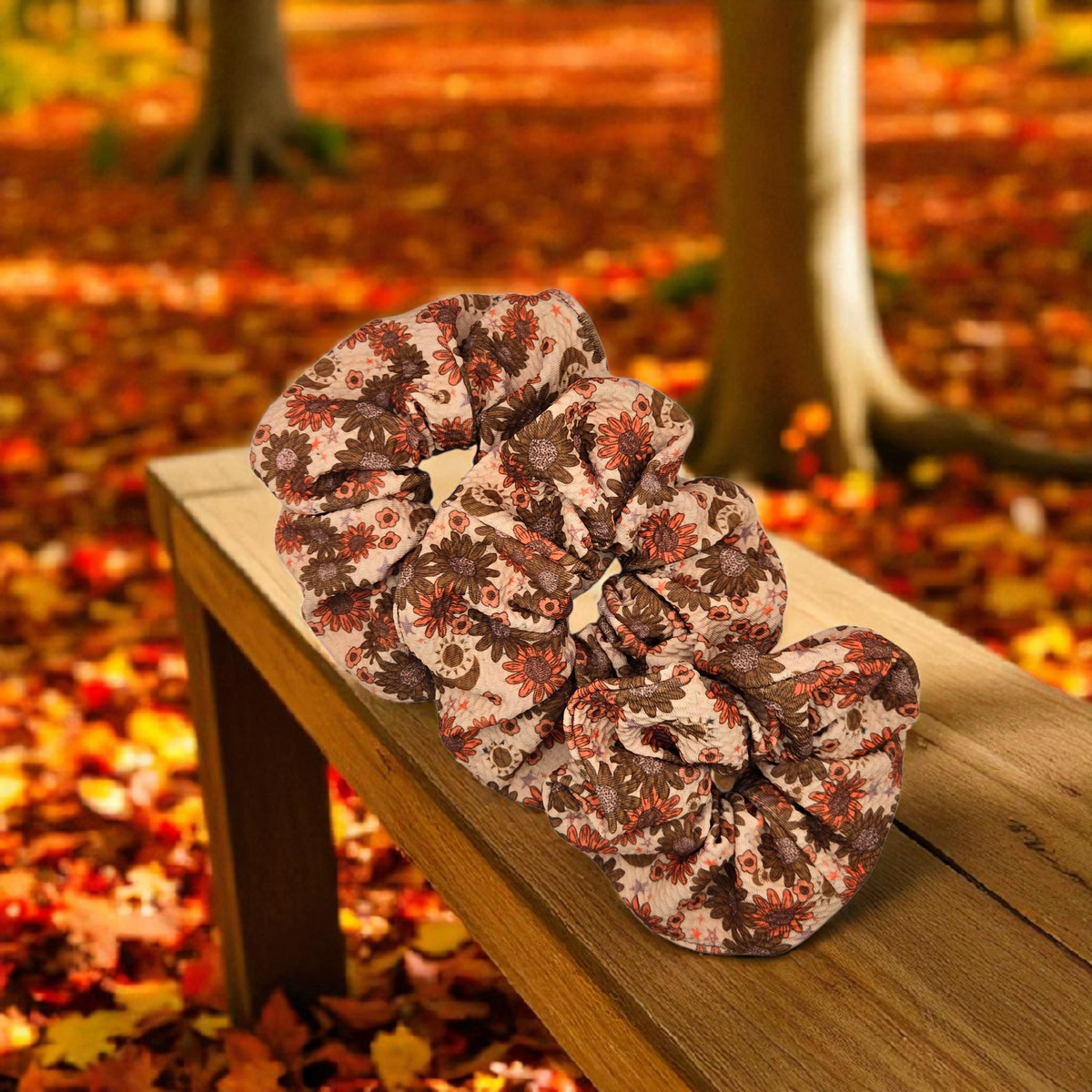 Whiskers n Bows vintage floral scrunchie in rust and brown on a wooden bench against an autumn forest background