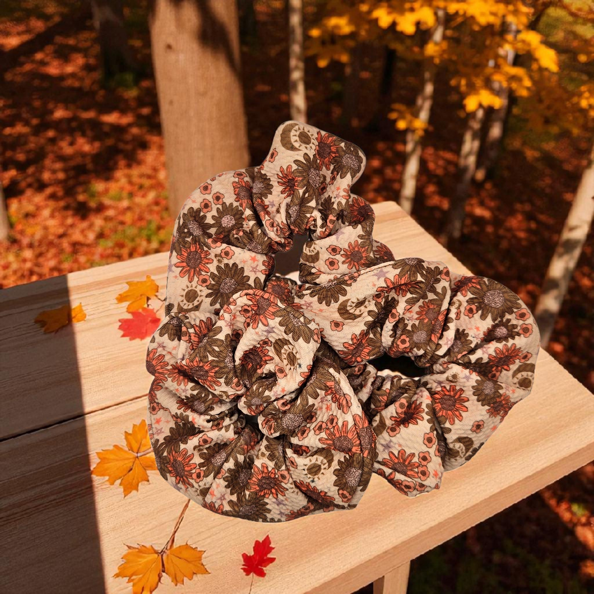 Whiskers n Bows vintage floral scrunchie in rust and cream fabric, displayed on a wooden surface with autumn leaves.